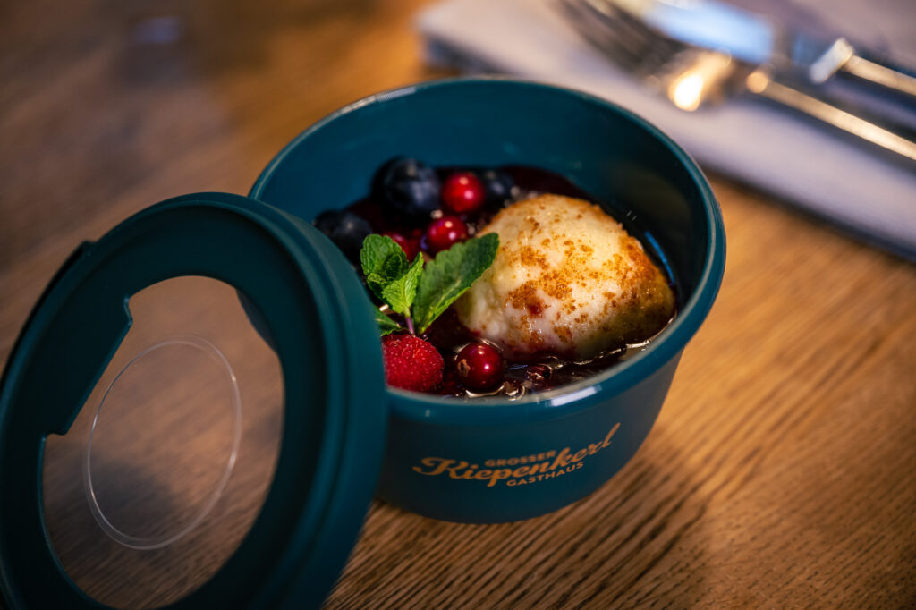 Dessert in einer Petrolfarbenden Mehrwegbox – Topfenknödel mit feinem Beerenkompott