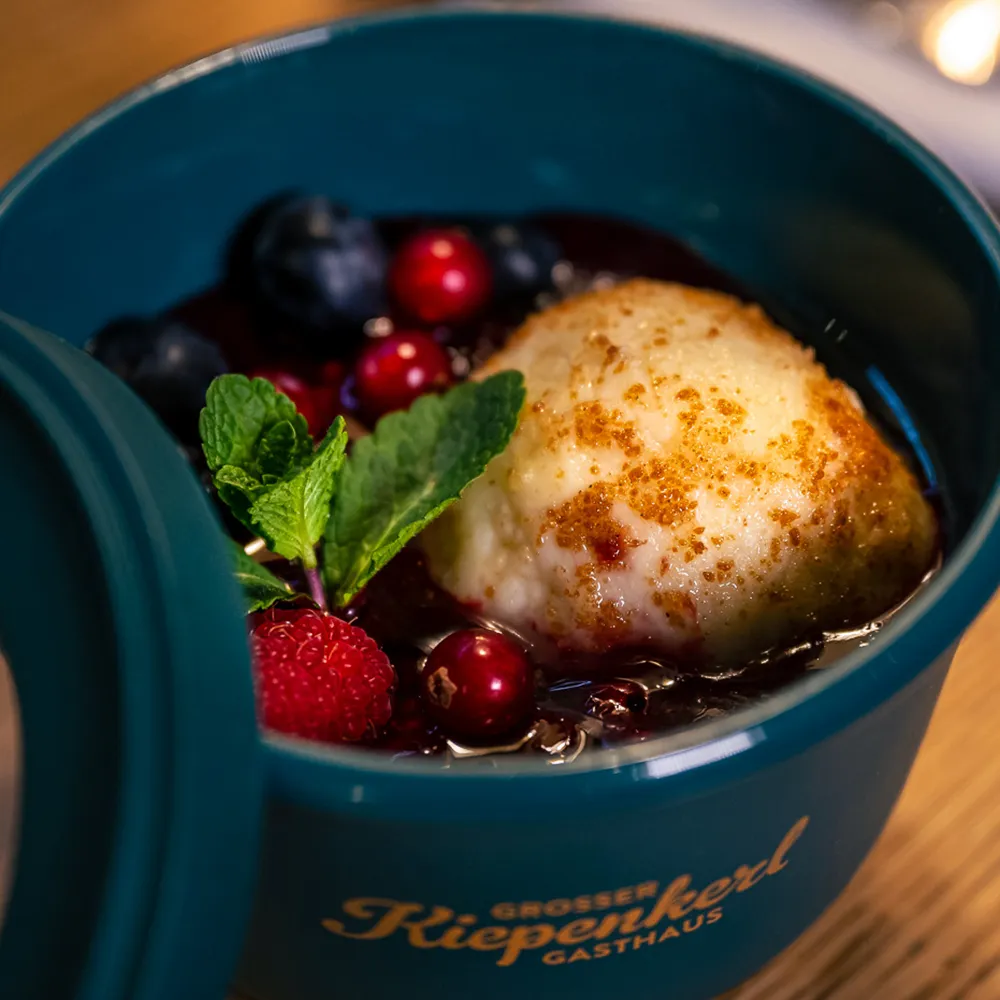 Dessert in einer Petrolfarbenden Mehrwegbox – Topfenknödel mit feinem Beerenkompott.